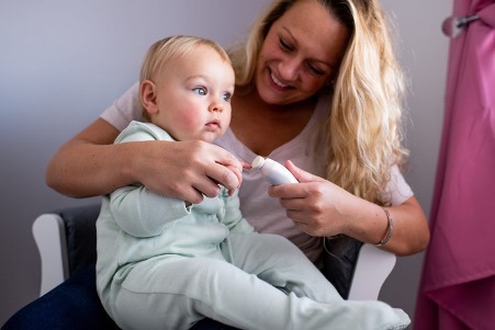 Lifestyle image of mother using nail file on baby